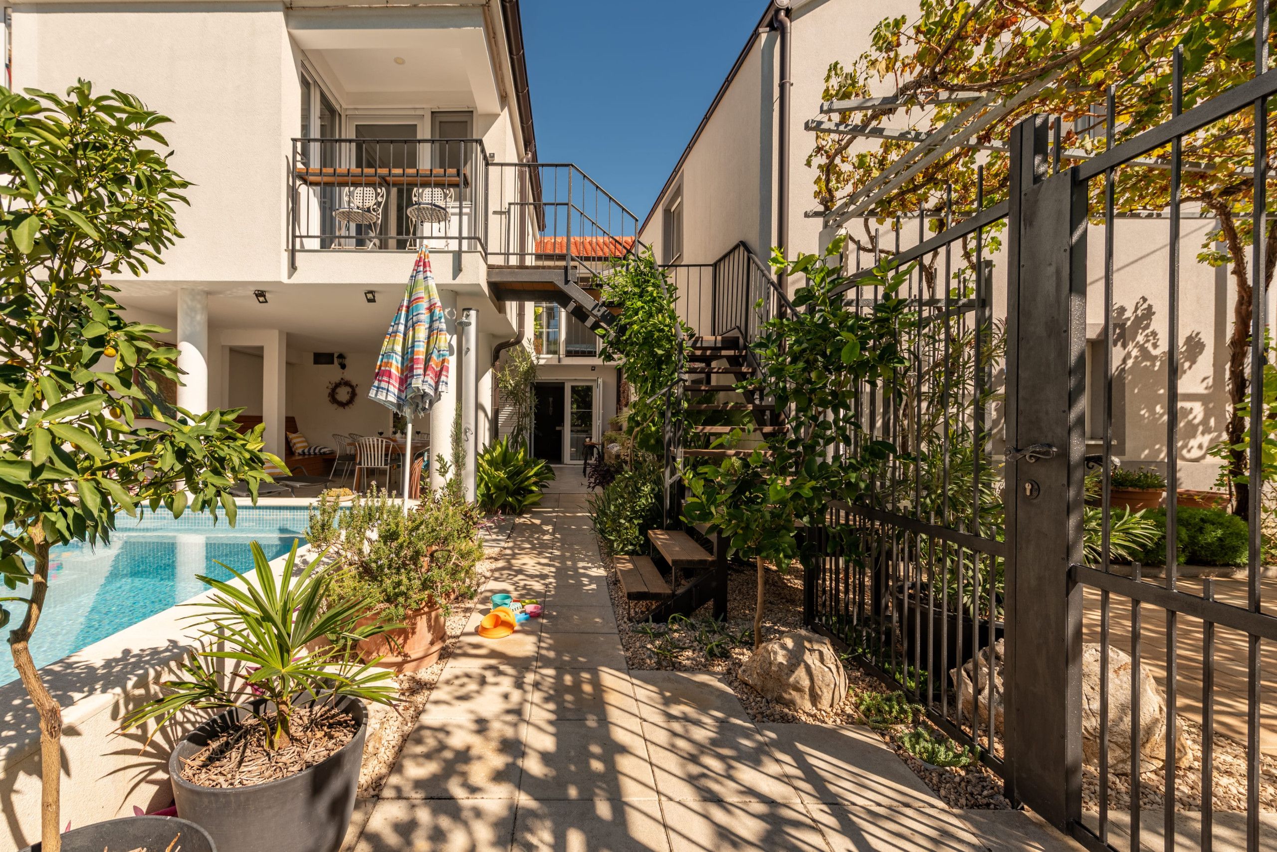 A residential property with a swimming pool, outdoor seating, and a gated entrance.