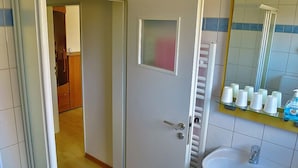 Un bagno con un lavandino bianco, uno specchio e articoli da toilette su uno scaffale.
