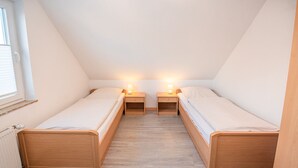 Una camera del dormitorio con due letti singoli, poggiatesta in legno e comodini con lampade.