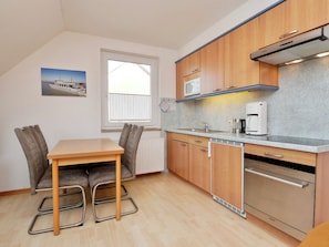 A compact kitchen with wooden cabinets, a microwave, a coffee maker, and a dishwasher.