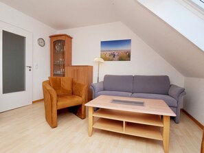 A room with a wooden cabinet, a sofa, a small table, and a picture on the wall.