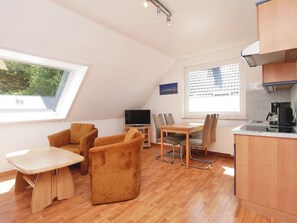 Kompakti oleskelutila, jossa on ruokailualue, televisio ja pieni keittiö.