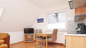 A small, modern apartment with a dining area, a kitchen, and a TV. - Haus Wirdemann Wohnung 2 (Norderney)