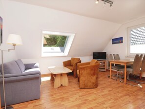 A modern living room with a sofa, chairs, a TV, and a dining table. - Haus Wirdemann Wohnung 2 (Norderney)