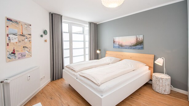 Ein modernes Schlafzimmer mit einem großen Bett, einer Nachttischlampe und Bildern an den Wänden.