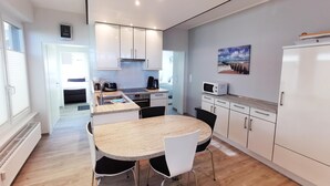 Une cuisine moderne avec des meubles blancs, un plan de travail en granit et un coin repas comprenant une table ronde et des chaises.