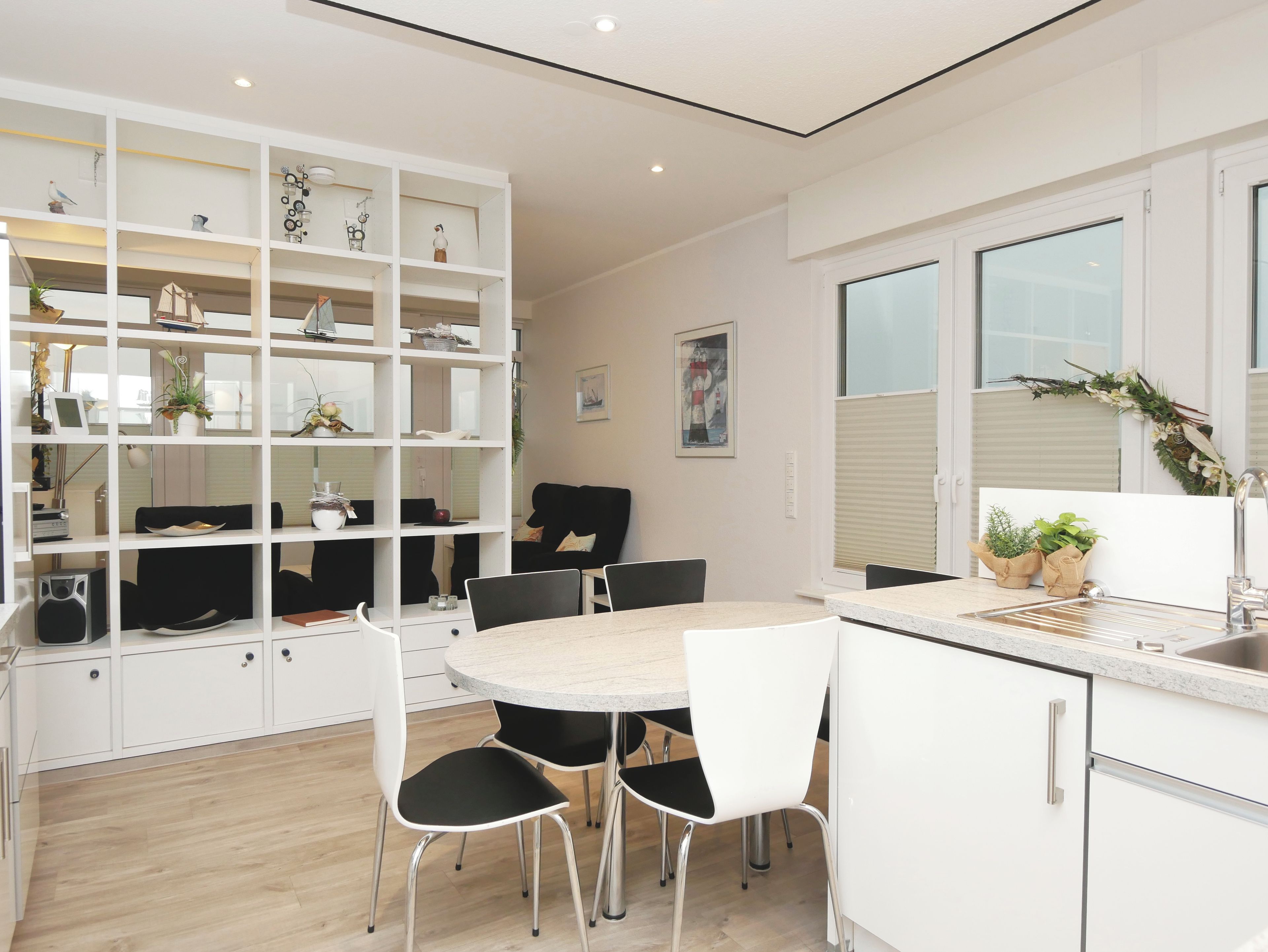 Une cuisine moderne avec des meubles blancs, une table de salle à manger ronde et des chaises noires.