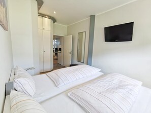 A hotel room with two beds, a TV, a wardrobe, and a mirror.