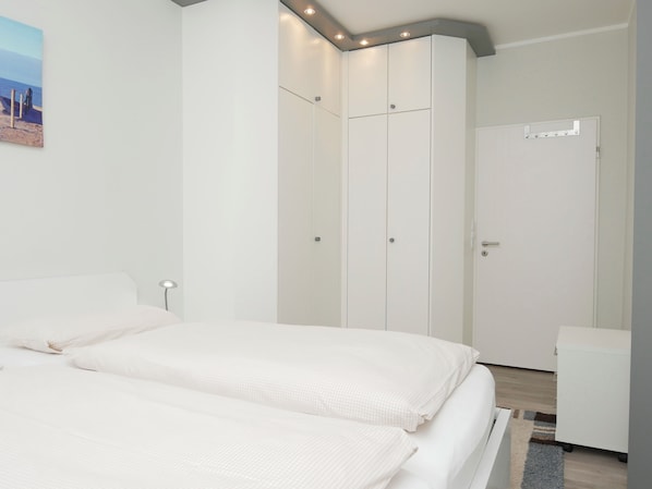 A bedroom with two beds, a wardrobe, and a desk. - Haus Großer Seekaiser (Norderney)