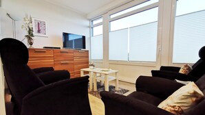 Un salon moderne avec un ensemble de canapés, un téléviseur et un meuble en bois.