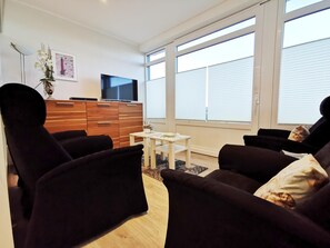 A modern living room with a sofa set, a TV, and a wooden cabinet.