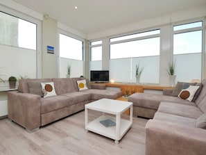Un salon moderne avec un canapé d’angle, une table basse et un téléviseur à écran plat.
