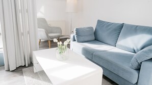 Moderni olohuone, jossa on vaaleansininen sohva, valkoinen sohvapöytä, jossa on maljakko täynnä kukkia, ja harmaa nojatuoli.