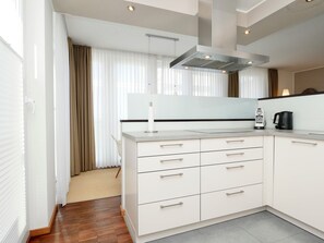 Une cuisine moderne avec des meubles blancs, une hotte en acier inoxydable et une machine à café.