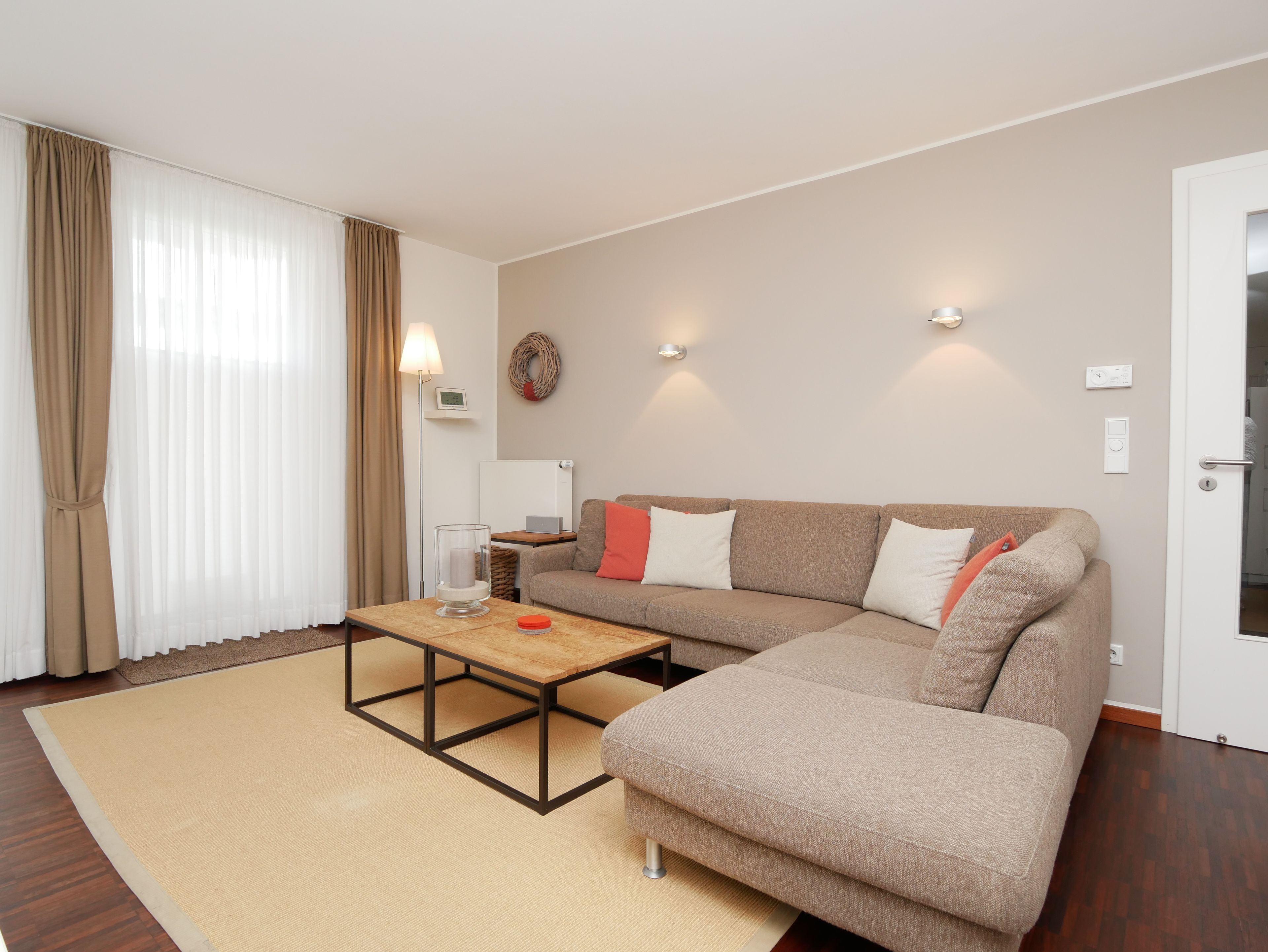 Een moderne woonkamer met een hoekbank, een salontafel en een vloerlamp.