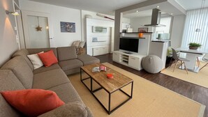 Uma sala de estar moderna com um sofá seccional, uma mesa de centro e uma televisão.