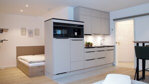 A compact, modern room with a bed, kitchenette, and a small dining area. - Wohnung Nr. 3 / Rübsamen-lüttenberg (Norderney)