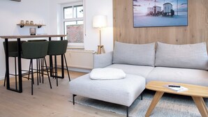 A modern living room with a sofa, a coffee table, and a dining area with chairs. - Wohnung Nr. 3 / Rübsamen-lüttenberg (Norderney)