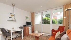 A modern living room with a dining area, a TV, and a sofa. - Haus Ulrichs Wohnung 1 b (Norderney)