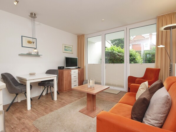 Ein modernes Wohnzimmer mit Essbereich, Fernseher und einer Couch.