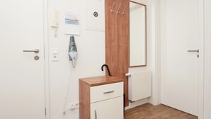 A room with a wooden cabinet, a mirror, a calendar, a hairdryer, and a radiator. - Haus Ulrichs Wohnung 1 b (Norderney)
