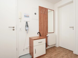 Et værelse med et træskab, et spejl, en kalender, en hårtørrer og en radiator.