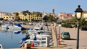 A marina with boats docked, a street with buildings, and a lamp post. - STELLA MARINA holiday apartment, 450 meters from the sea, independent entrance (portoscuso)