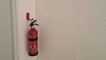 Un extincteur rouge fixé sur une porte blanche.