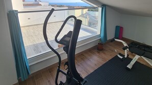A room with a view of the sea, a ceiling fan, a treadmill, and a yoga mat. - STELLA MARINA holiday apartment, 450 meters from the sea, independent entrance (portoscuso)
