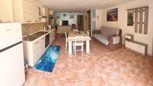 A compact living space with a kitchen, dining area, and a sofa. - STELLA MARINA holiday apartment, 450 meters from the sea, independent entrance (portoscuso)