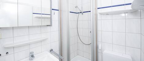 A modern bathroom with a glass-enclosed shower, a white sink with a mirror above, and a toilet with a blue stripe.