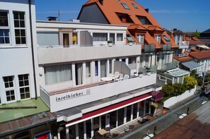 Un immeuble à plusieurs étages abritant un restaurant au rez-de-chaussée, doté de grandes fenêtres et d’une terrasse.