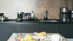 A modern kitchen with a coffee maker, kettle, and a fruit bowl on the counter. - Haus Jantje Mö Wohnung 5 (Norderney)