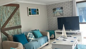 A modern living room with a sofa, coffee table, and a television. - whalecome house Bongaree (Brisbane)