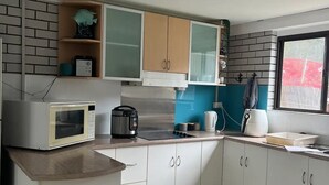 A modern kitchen with white cabinets, a microwave, a kettle, and a coffee maker. - whalecome house Bongaree (Brisbane)