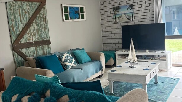 A living room with a sofa, coffee table, and a TV. - whalecome house Bongaree (Brisbane)