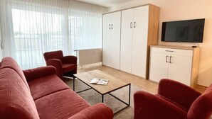 En moderne stue med et rødt sofasæt, et sofabord og et fjernsyn ophængt på væggen.