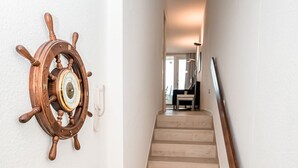 A staircase with a wooden ship's wheel decoration on the wall. - Haus Meeresbrandung Wohnung 23 (Norderney)