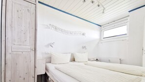 Una habitación con cama, mesitas de noche, un armario y una ventana.