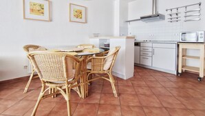 A modern kitchen with white cabinets, a built-in microwave, and a small wooden shelf. - Villa Nordland Wohnung 6 (Norderney)