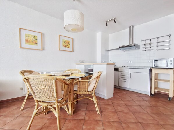 A modern kitchen with white cabinets, a built-in microwave, and a small wooden shelf.