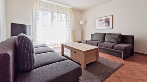 A living room with a sofa, a coffee table, and a TV. - Villa Nordland Wohnung 6 (Norderney)
