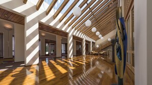 A spacious lobby with wooden floors, a high ceiling with skylights, and a modern art installation. - LILIENBERG (Ermatingen)