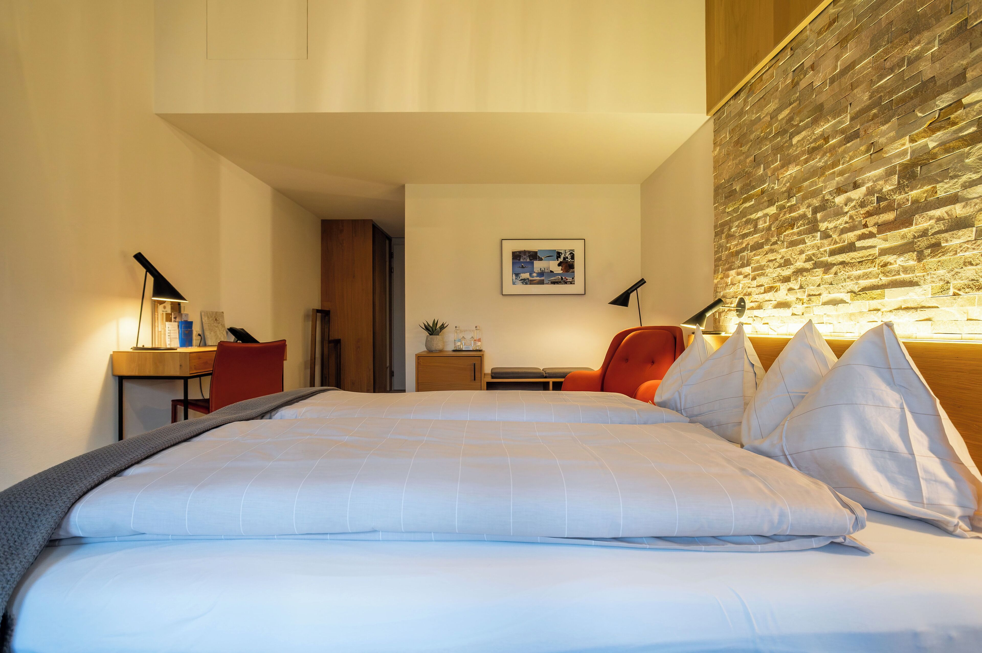 A hotel room with a large bed, a desk, a chair, and a wall with a textured design.