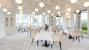 A spacious dining area with multiple tables and chairs, large windows, and hanging spherical light fixtures. - LILIENBERG (Ermatingen)