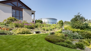 A modern house with a well-maintained garden, a circular water feature, and a clear sky. - LILIENBERG (Ermatingen)