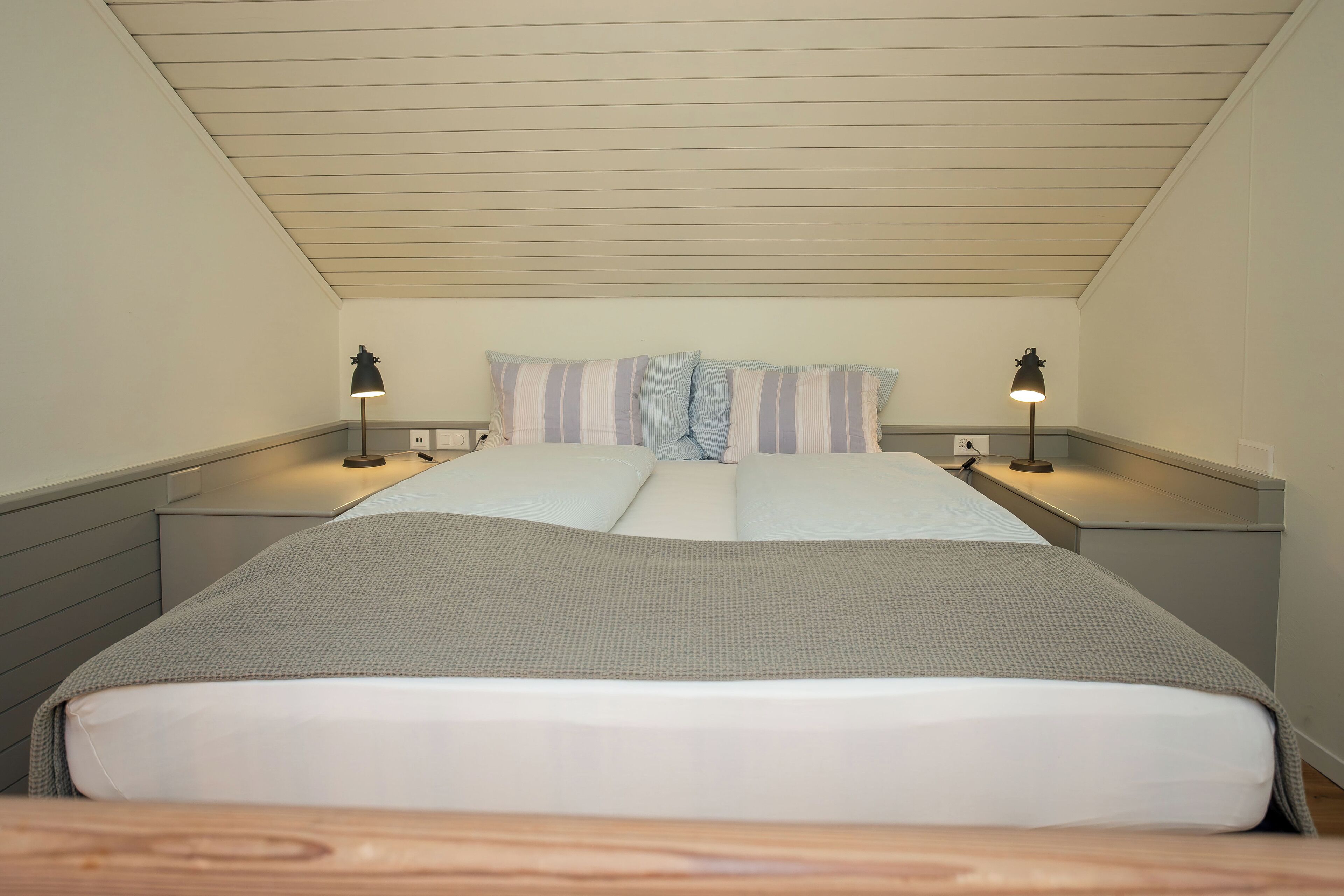 Un dormitorio con una cama, dos mesitas de noche y dos lámparas.