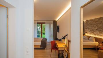 Un hotel moderno con un escritorio de madera, una silla roja, una cama y vistas a zonas verdes.