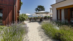 An outdoor patio area with tables and chairs, surrounded by lavender plants and a view of the sea. - LILIENBERG (Ermatingen)