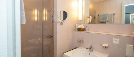A modern bathroom with a glass-enclosed shower, a white sink, and a large mirror.